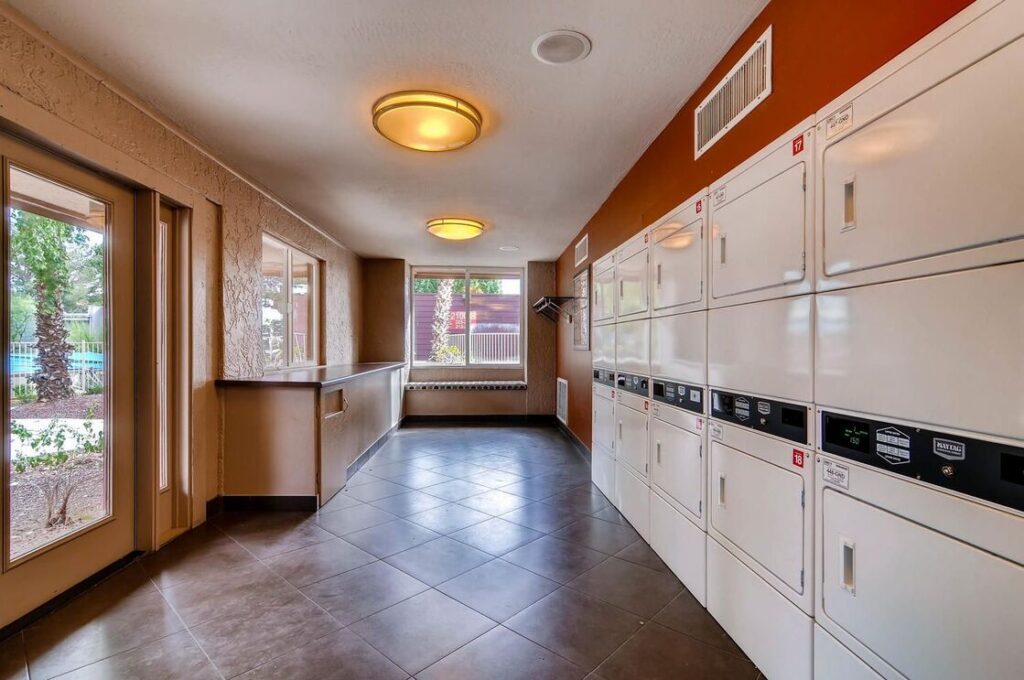 group laundry facility with lots of dryers and a folding station