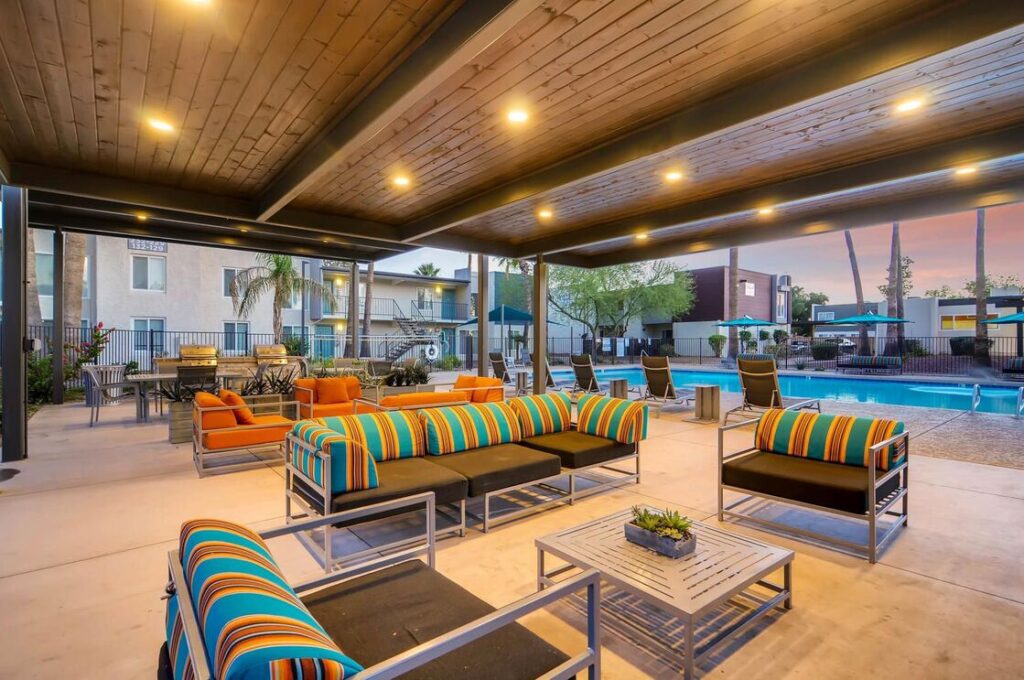 A covered outdoor pavilion with bright orange, blue, and black pillows with lounge chairs and couches at Scottsdale Gateway's apartments near Scottsdale, AZ